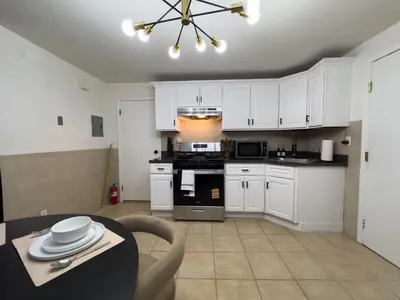 a kitchen with white cabinets and a table and a dining room at Elegant NYC View Stay Park Free 6 beds Sleep 8 in Kearny