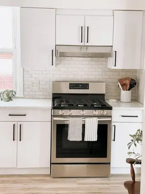 a kitchen with a stainless steel stove and white cabinets at Garden Oasis 3BR 23min NYC PATH in Harrison