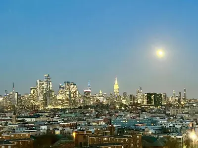 a view of a city at night with the moon at Renovated private urban flat - 20 min to Manhattan NYC in Jersey City