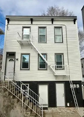 a white house with stairs on the side of it at Renovated private urban flat - 20 min to Manhattan NYC in Jersey City