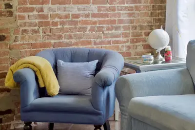 a blue chair with a blanket on it next to a table at Stay In Times Square! 2-Bedroom Apartments in New York
