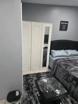 a bedroom with a bed and a glass table at A newly built detached studio apartment with queen size bed in Irvington
