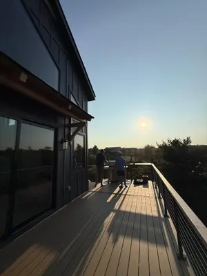two people standing on the deck of a house at Gray Owl Lodge- A Serene Lakefront Retreat on Sleepy Hollow Lake near Hudson NY in Athens