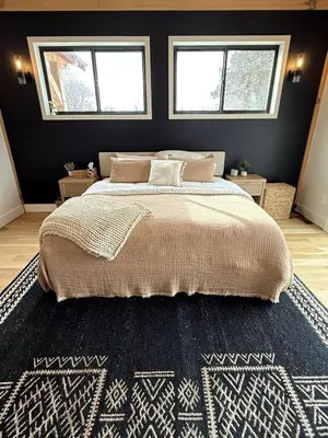 a bedroom with a large bed with a blue rug at Gray Owl Lodge- A Serene Lakefront Retreat on Sleepy Hollow Lake near Hudson NY in Athens