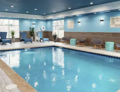 a large swimming pool in a hotel lobby with chairs and tables at Hampton Inn & Suites By Hilton North Haven in North Haven