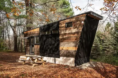 a tiny house in the woods with a picnic table at The Outlier Inn in Woodridge