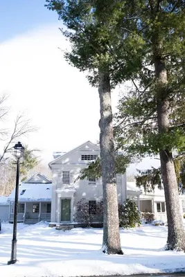 a white house with two trees in the snow at ButtonBall Inn in South Egremont