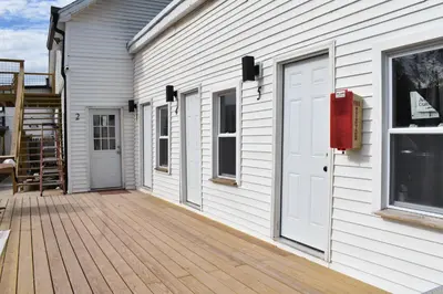 a white house with a wooden porch with a door at Tannersville Village Room 1 in Tannersville