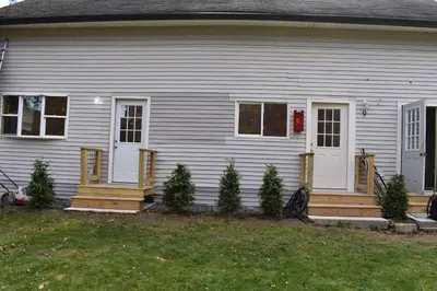 a white house with a porch with christmas trees at Tannersville Village Room 1 in Tannersville
