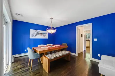 a dining room with blue walls and a wooden table at Zen Lake House in Greenwood Lake