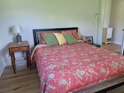 a bedroom with a bed with a red comforter at Cozy Country Cottage in Norwich