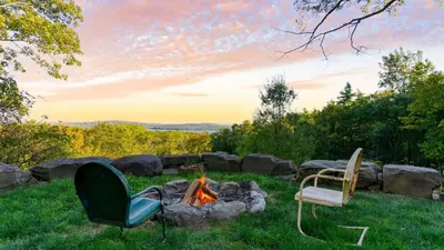 two chairs and a camp fire in the grass at Modern Catskills Escape w Open Living Steam Shower Hot Tub w Mountain Views Minutes from Woodstock Trails Suncliff Vista in Shokan