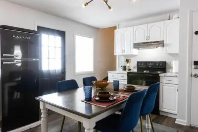 a kitchen with a table with chairs and a black refrigerator at Private Classy 2nd Flr 3 Bed Apt Near Downtown in Torrington