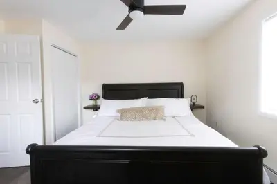 a bedroom with a black and white bed with a ceiling fan at Private Classy 2nd Flr 3 Bed Apt Near Downtown in Torrington