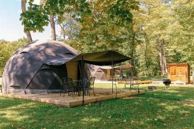 a tent with chairs and a table in a field at Cozy Mountain Dome Escape in the Catskills in Gilboa