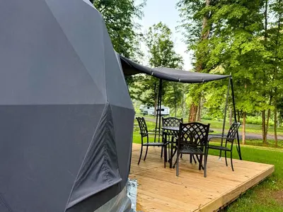 a tent with chairs and tables on a wooden deck at Cozy Mountain Dome Escape in the Catskills in Gilboa