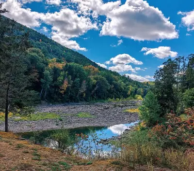 a river in the middle of a valley with trees at Luxury Catskill Mountains Dome Retreat in Gilboa