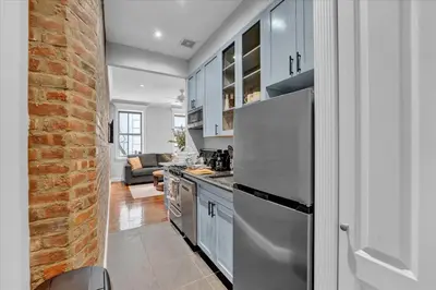 a kitchen with a refrigerator and a brick wall at Stylish 3BR-2BA in Gramercy -Modern & Central in New York