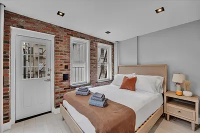 a bedroom with a bed and a brick wall at SoHo Designer 2BR w balcony in New York