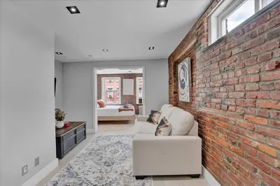 a living room with a brick wall and a couch at SoHo Designer 2BR w balcony in New York