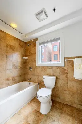 a bathroom with a toilet and a tub and a window at Modern 3BR Townhouse with Private Rooftop & Parking Minutes to NYC in Hoboken