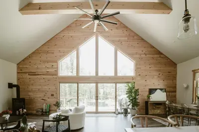 a room with a large window and a ceiling fan at Luxe Modern Cabin with Pond, Fire Pit, Hiking, near Bethel Woods in Narrowsburg