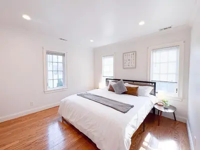 a white bedroom with a large bed and two windows at Family-Friendly 4 Bed 3 Bath Downtown Delight in Stamford