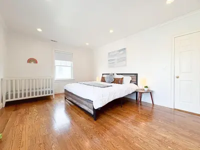 a white bedroom with a bed and a wooden floor at Family-Friendly 4 Bed 3 Bath Downtown Delight in Stamford