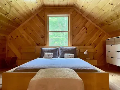 a bed in a wooden room with a window at Red Tail Ridge in North Branch