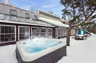 a hot tub in the snow in front of a building at The birch House Heated Pool, Sauna, Hot Tub & More in Dover