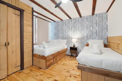 two beds in a room with wooden floors at The birch House Heated Pool, Sauna, Hot Tub & More in Dover