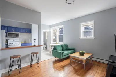 a living room with a green couch and a kitchen at One BR near Metlife with Laundry & Parking in Lodi