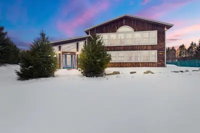 a house in the snow with trees in front of it at Myrtle Villa 7BR Near Mount Snow with Indoor Heated Endless Style Pool Outdoor Hot Tub in Dover