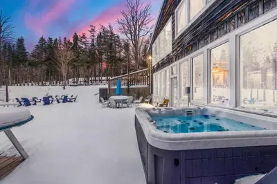 a hot tub sitting outside of a building in the snow at 12BR Villa Near Mount Snow Sleeps 32 Hot Tub & Indoor Pool in Dover