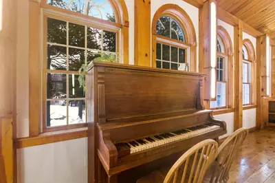 a piano sitting in a room with windows at 12BR Villa Near Mount Snow Sleeps 32 Hot Tub & Indoor Pool in Dover