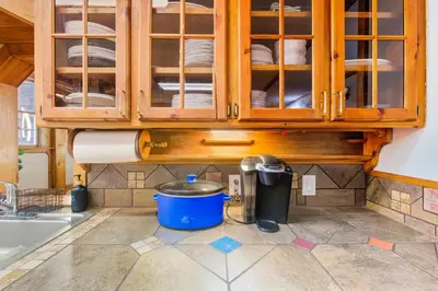 a kitchen with wooden cabinets and a bucket on the floor at 12BR Villa Near Mount Snow Sleeps 32 Hot Tub & Indoor Pool in Dover