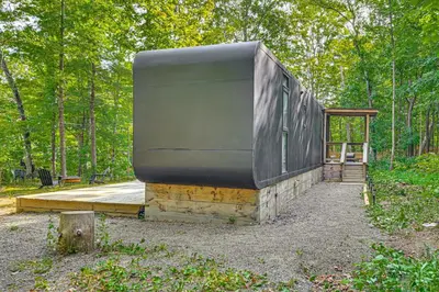 a house sitting on a wooden platform in the woods at Waterfront Durham Getaway with Deck and Trails! in East Durham