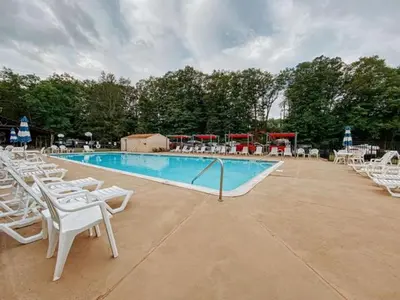 a swimming pool with white chairs and a bunch ofitures at Boutique Glamping Dome in the Catskill Mountains in Gilboa