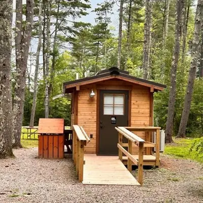 a small cabin in the woods with a bench at Boutique Glamping Dome in the Catskill Mountains in Gilboa
