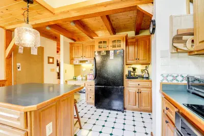 a kitchen with wooden cabinets and a black refrigerator at 10 Mi to Mt Snow! Grand Estate Built to Entertain in Wilmington