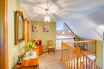 a hallway with a staircase with a mirror and a chair at Game Room, Hot Tub! Year-Round Dover Retreat in West Dover