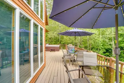 a deck with chairs and an umbrella on a house at Game Room, Hot Tub! Year-Round Dover Retreat in West Dover