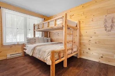 a bedroom with a bunk bed in a log cabin at Luxury Log Cabin Lakefront, Game room & Fire Pit, in Schenevus