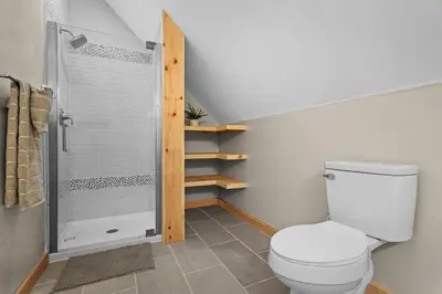 a bathroom with a toilet and a walk in shower at Luxury Log Cabin Lakefront, Game room & Fire Pit, in Schenevus