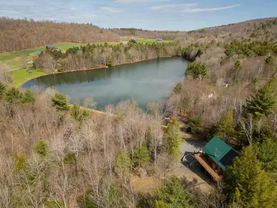 an aerial view of a lake in the woods at Luxury Log Cabin Lakefront, Game room & Fire Pit, in Schenevus