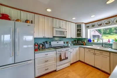 a kitchen with white appliances and wooden cabinets at Pet-Friendly Catskills Home with Serene Pond! in Jefferson