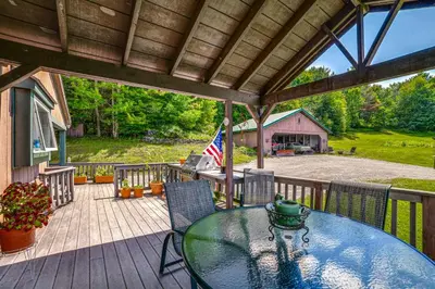 a patio with a glass table and chairs on a deck at Pet-Friendly Catskills Home with Serene Pond! in Jefferson