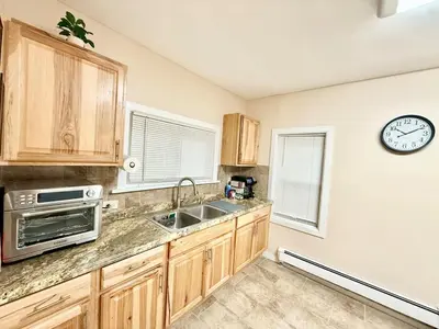 a kitchen with wooden cabinets and a clock on the wall at Charming Milford Montague Riverway Cottage in Montague