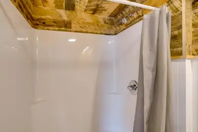 a bathroom with a shower curtain and a wooden ceiling at Cabin on Crooked Lake Ski, Skate and Explore! in Averill Park