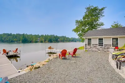 a house with chairs and a dock on a lake at Cabin on Crooked Lake Ski, Skate and Explore! in Averill Park